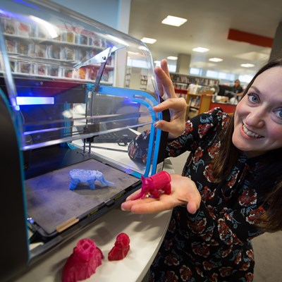 Picture of  a librarian holding examples of 3D printing models printed in a Scottish public library